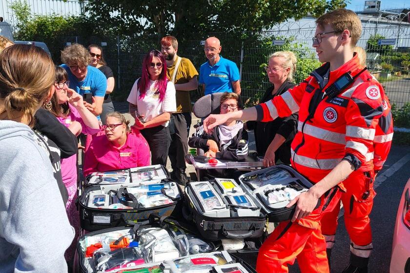 Teilnehmende des Duo Day erhalten bei den Johannitern Hamburg praxisnahe Einblicke in Erste Hilfe und Rettungsdienst. Ein Rettungsdienstmitarbeiter erklärt medizinische Ausrüstung an einem Einsatzfahrzeug im Freien.
