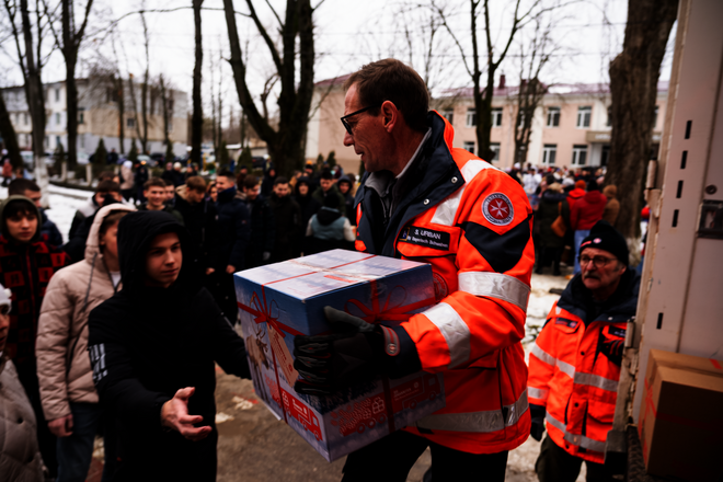 Johanniter verteilen Päckchen vom Johanniter-Weihnachtstrucker aus einem Lkw an Menschen