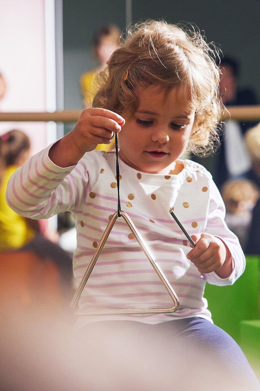 Kind spielt mit Triangel.