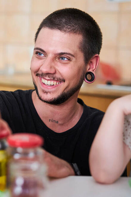 Ein Erzieher kniet am Tisch neben einem Kind