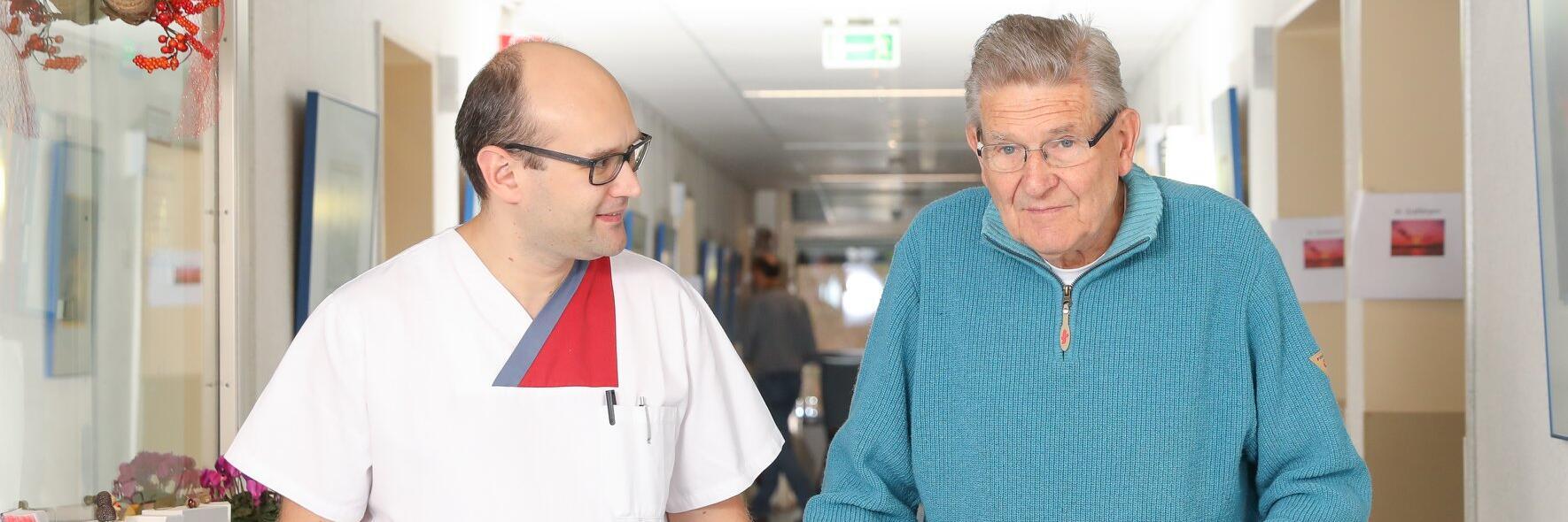 Pfleger mit älteren Mann mit Gehhilfe