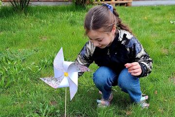 Ein Mädchen steckt ein Windrad in den Boden