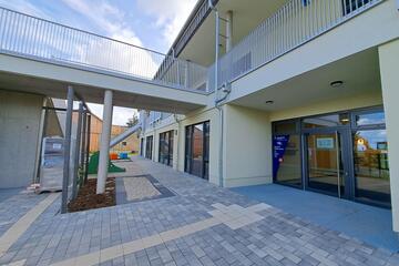 Der Eingangsbereich der Kita mit Ausblick auf den Spielplatz mit Rutsche und Sandkasten.