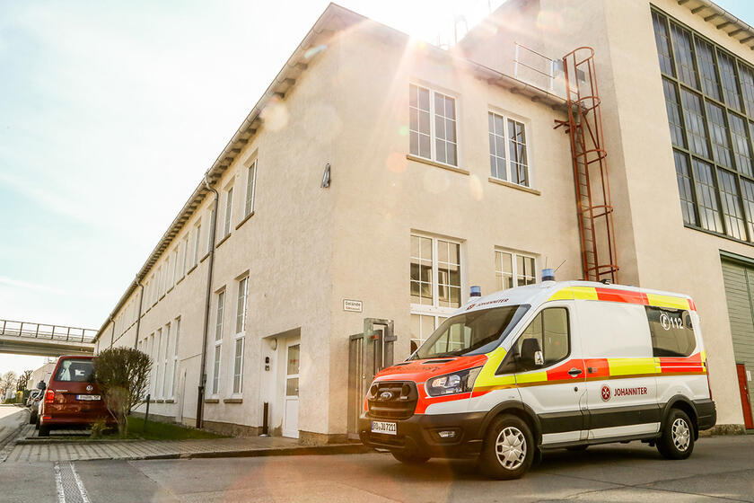 Krankentransportwagen vor hellem Gebäude mit Sonne im Hintergrund