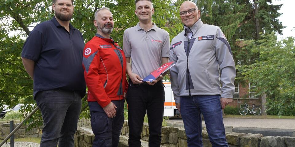 Vier Männer im Grünen. Einer hält ein Zertifikat