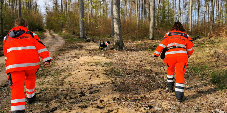 Zwei Mitglieder der Rettungshundestaffel mit Hund auf der Suche
