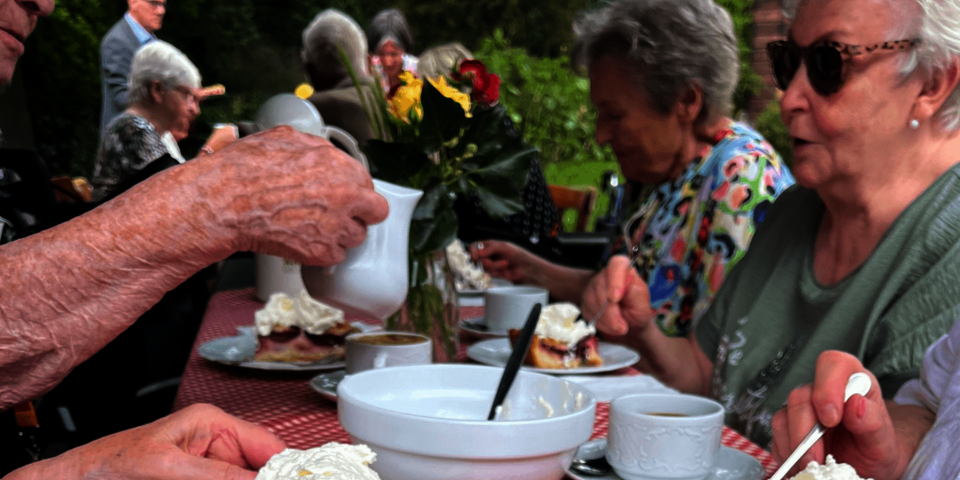 Detail eines gedekcten Kaffeetischs mit Obstkuchen und Sahne
