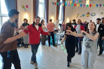 Eine Gruppe von Personen tanzt in einem geschmückten Saal.