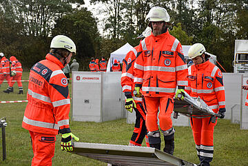 Mehrere Einsatzkräfte bewältigen gemeinsam einen Trageparcours. 