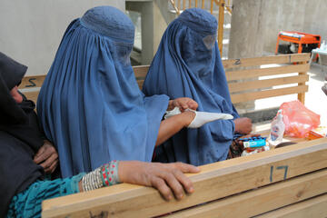 Zwei Frauen erhalten Handschuhe und Desinfektionsmaterial