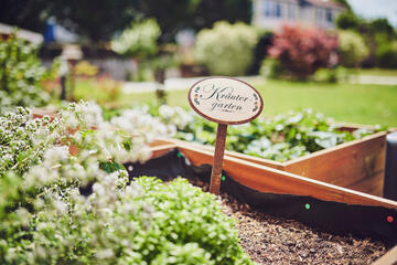 Blick auf ein Hochbeet mit Kräutern und deren Bezeichnung auf einen kleinen Schild