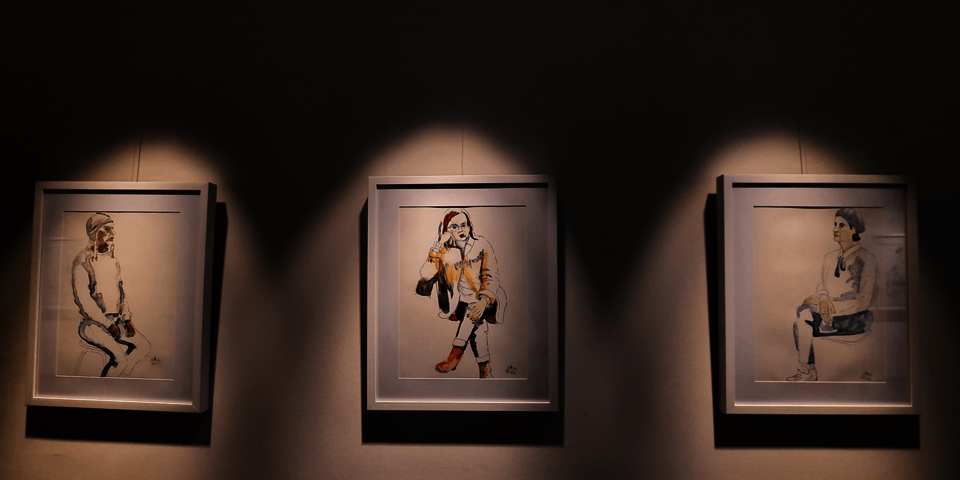 Drei Aquarellbilder, die von Scheinwerfern beleuchtet sind