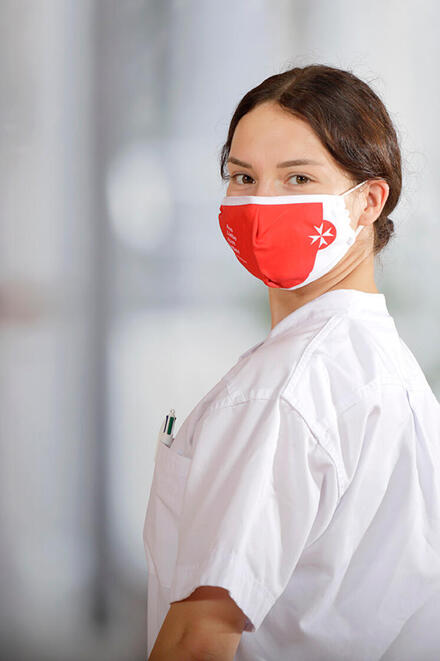 Junge Frau mit weißer Kleidung und Mund-Nasen-Schutz