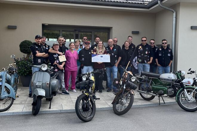 Mitglieder des Hells Bells Moped Club posieren zusammen mit Mitarbeitenden des Bruder-Gerhard-Hospiz. Im Vordergrund mehrere Mopeds  