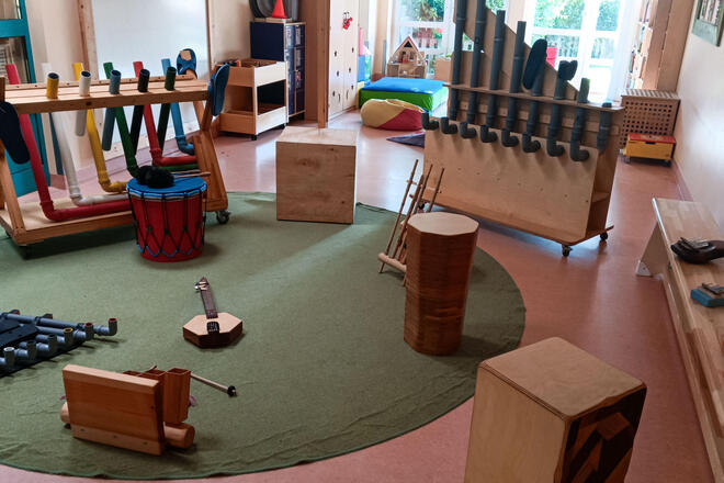 Im Gruppenraum der Johanniter-Kita Badendorfer Spatzennest liegen und stehen verschiedene selbstgebaute Musikinstrumente, wie z.B. eine Ukulele, Kalimbas oder ein Klopfophon.