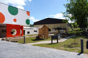 Eingangsbereich und kleiner Spielplatz der Kita mit schönem Holzspielhäuschen. 