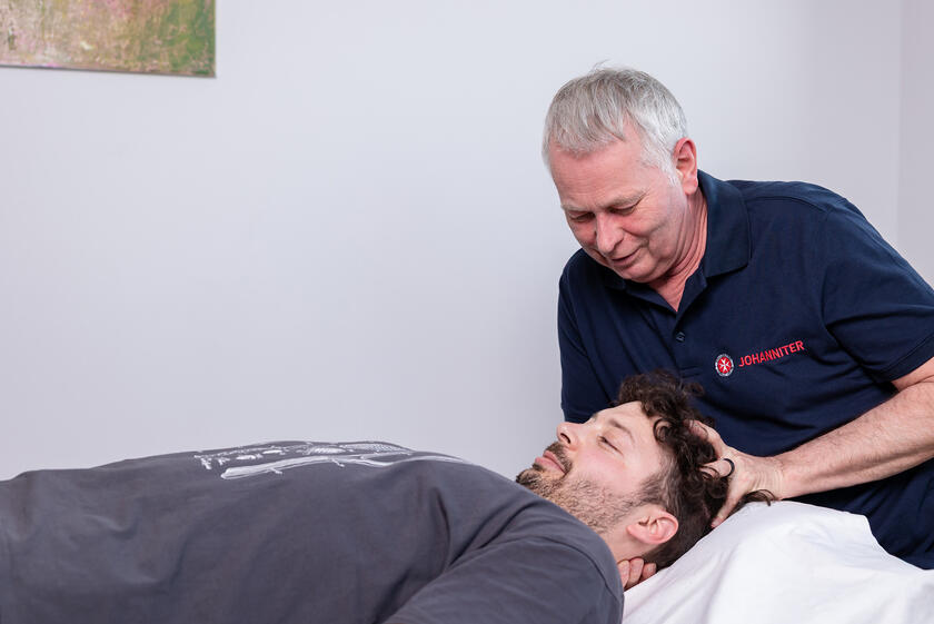 Ein Johanniter führt Manuelle Therapie an einem Patienten durch.