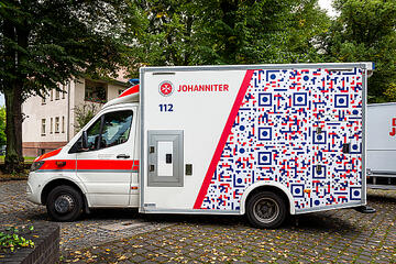 Ein beklebter Rettungswagen mit QR-Code-Design.