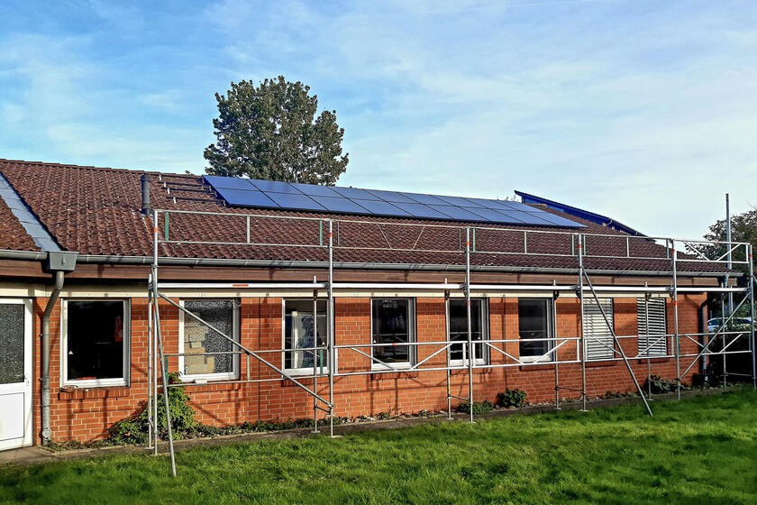 Auf dem Bild ist das Gebäude der Johanniter-Dienststelle in Eutin zu sehen. Davor steht ein Gerüst und auf dem Dach sind bereits einige Module installiert.