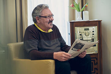 Ein älterer Herr wirf einen Blick in die Tageszeitung