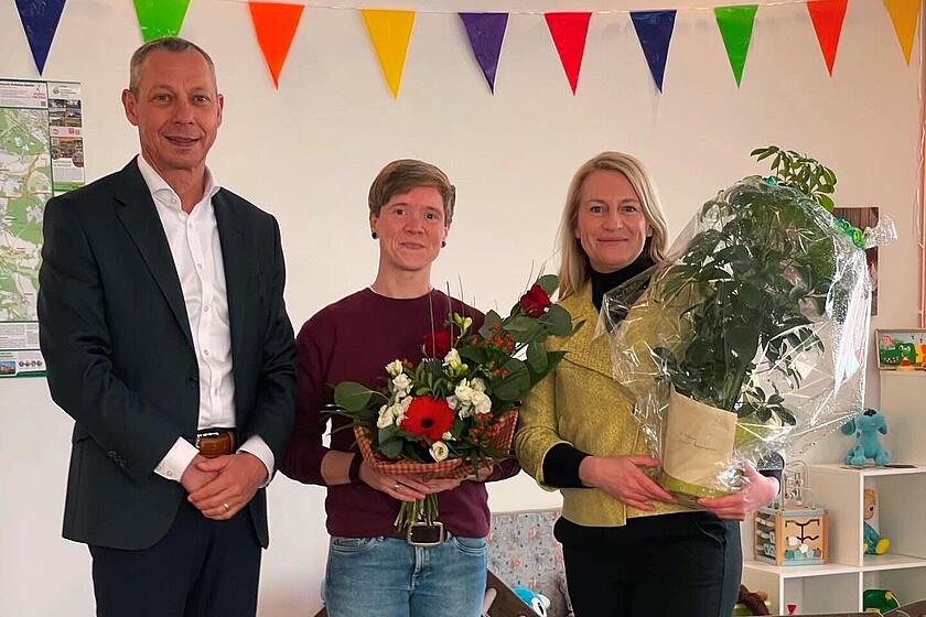 Ralf Boost überreicht zwei Mitarbeiterinnen der Begegnungsstätte in Michendorf zur Eröffnung ein paar Blumen.