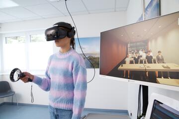 Patientin bei Therapiesitzung mit VR Brille Thema Vortrag vor vielen Personen 