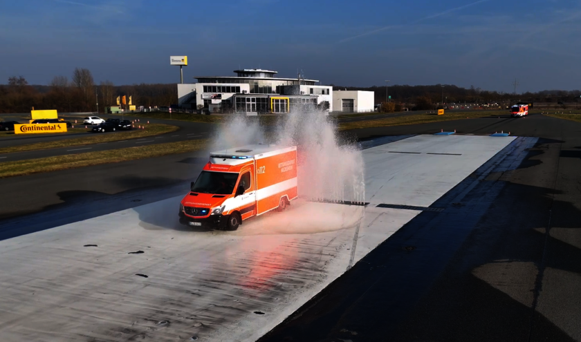 Ein Rettungswagen fährt durch Wasserfontänen