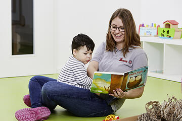 Eine Erzieherin liest einem Kind ein Buch vor.