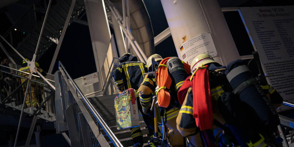 Ehrenamtliche Feuerwehrleute der Feuerwehr Speyer laufen die Treppe zur Boeing 747 im Technik Museum Speyer hoch.