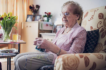 Eine Bewohnerin strickt mit vier Nadeln Socken