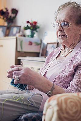 Eine Bewohnerin strickt mit vier Nadeln Socken