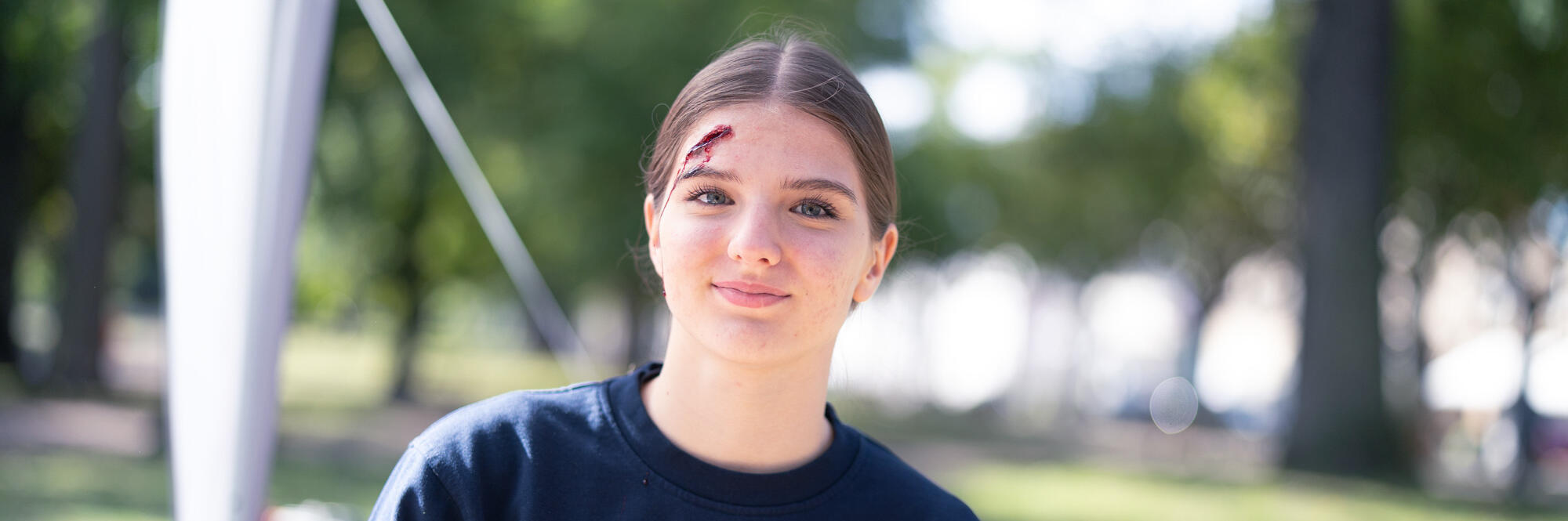 Eine Kraft der Realistische Unfalldarstellung der Johanniter hat eine geschminkte Wunde am Kopf.