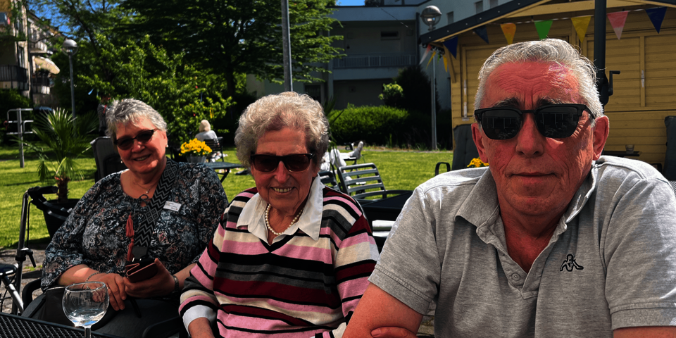 drei Personen mit Sonnenbrillen an einem Gartentisch