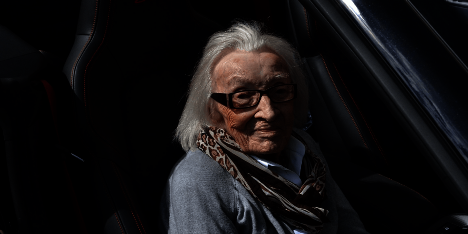 Eine weißhaarige alte Dame sitzt auf dem Beifahrersitz