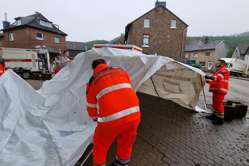 Einsatzkräfte der Johanniter bauen nach der Ahrtalflut in Stolberg ein Stangenzelt auf.