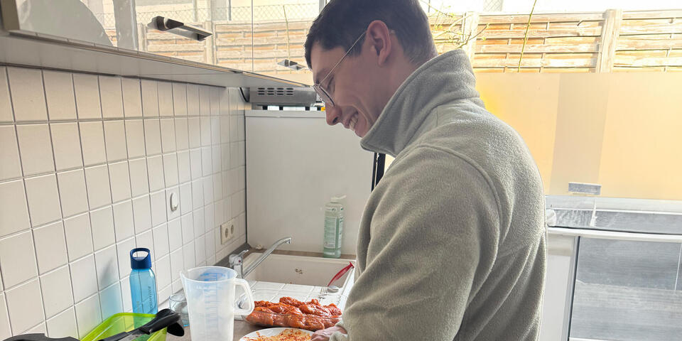 Ein junger Mann bereitet in einer Küche Grillgut vor