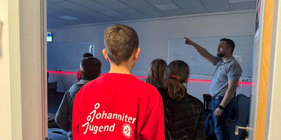 Ein Johanniter erklärt etwas. Kinder hören ihm zu.