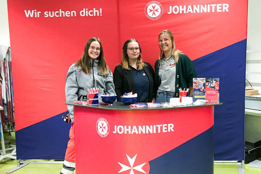 Drei Johanniterinnen an einem Messestand