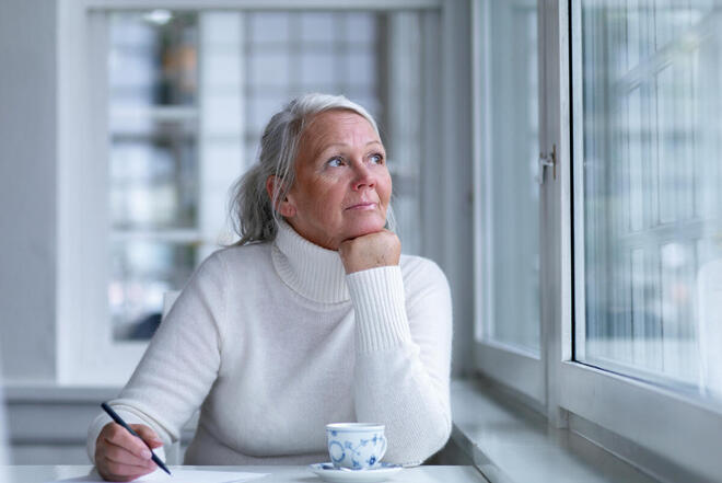 Ältere Dame nachdenklich am Tisch