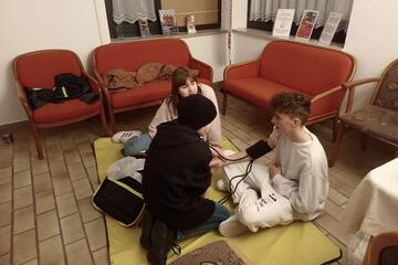 An einem Jungen wird geübt, wie man den Blutdruck misst.