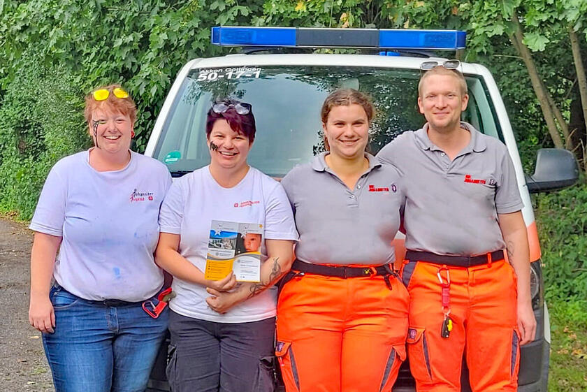  Zwei Johanniter und zwei Johanniterinnen vor einem Johanniter-Fahrzeug