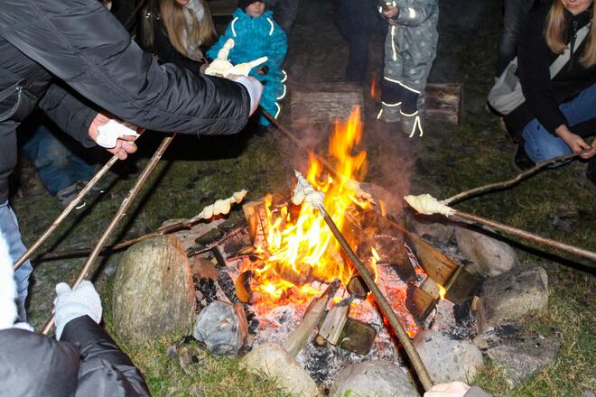 Kinder halten Stockbrot in ein Lagerfeuer.