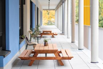 Ausblick auf die Terasse der Kita Lumi Natura mit Holzbänken im Vordergrund.