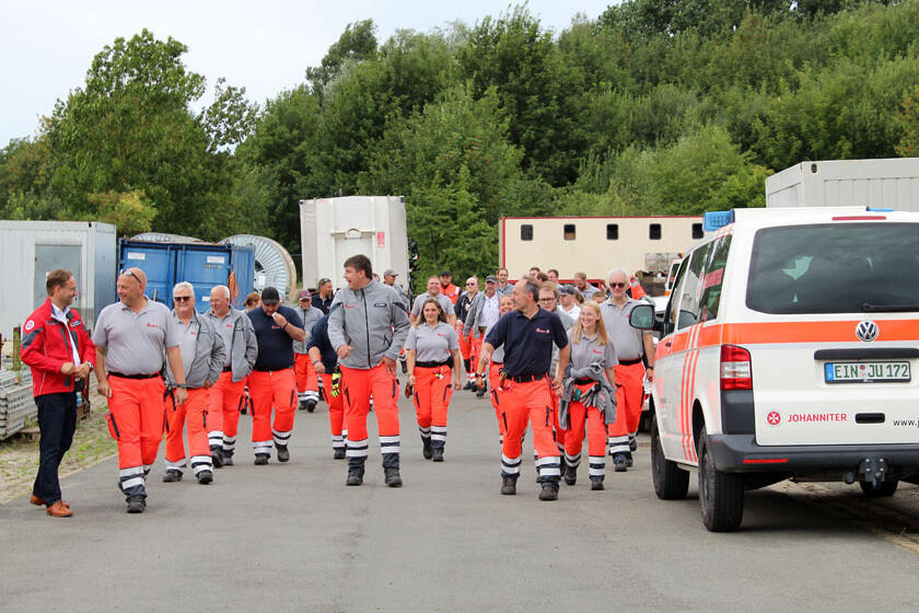 Johanniter kommen vom Einsatz zurück und laufen auf die Gäste und Kollegen/innen zu, die sie mit Applaus in Empfang nehmen.