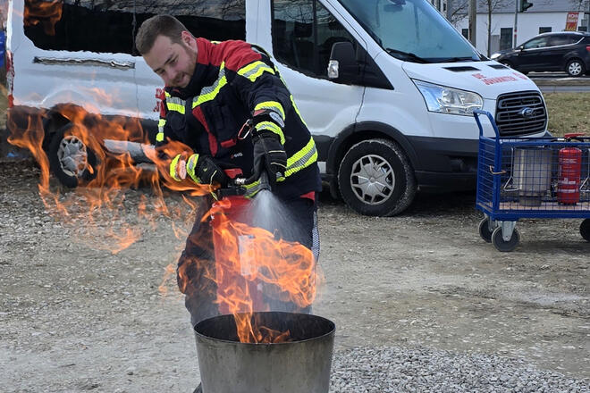 Bei einem Brandschutzhelfer Kurs in Bamberg führt der Kursleiter die Benutzung eines Feuerlöschers beim Löschen eines Feuers vor.
