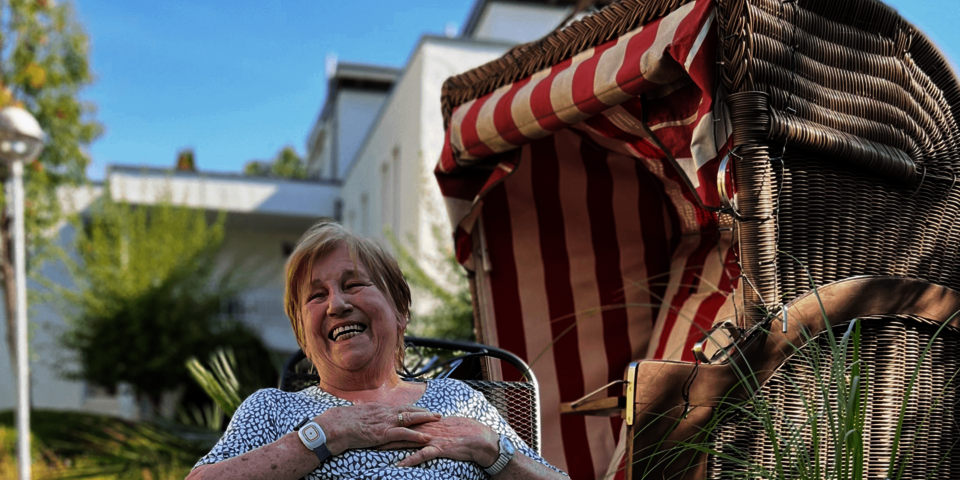 Eine Frau sitzt vor einem Strandkorb und lacht