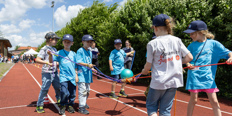Kinder der Johanniter-Jugend balancieren gemeinsam einen Ball mit Seilen.
