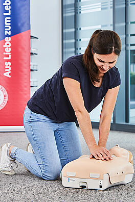 Eine junge Frau übt an einer Puppe die Herzdruckmassage
