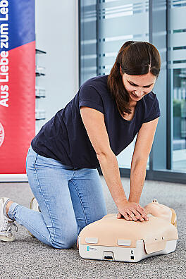 Eine junge Frau übt an einer Puppe die Herzdruckmassage