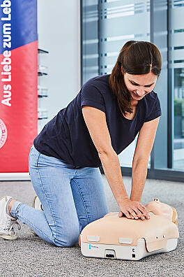 Eine junge Frau übt an einer Puppe die Herzdruckmassage